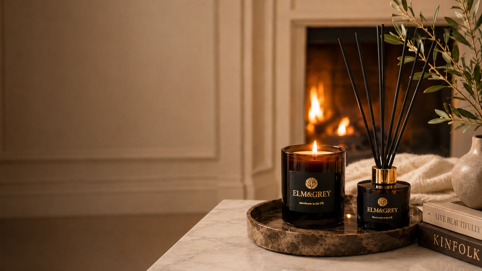 Luxury Elm & Grey amber candle and reed diffuser styled by a fireplace for a warm, calming home fragrance ritual
