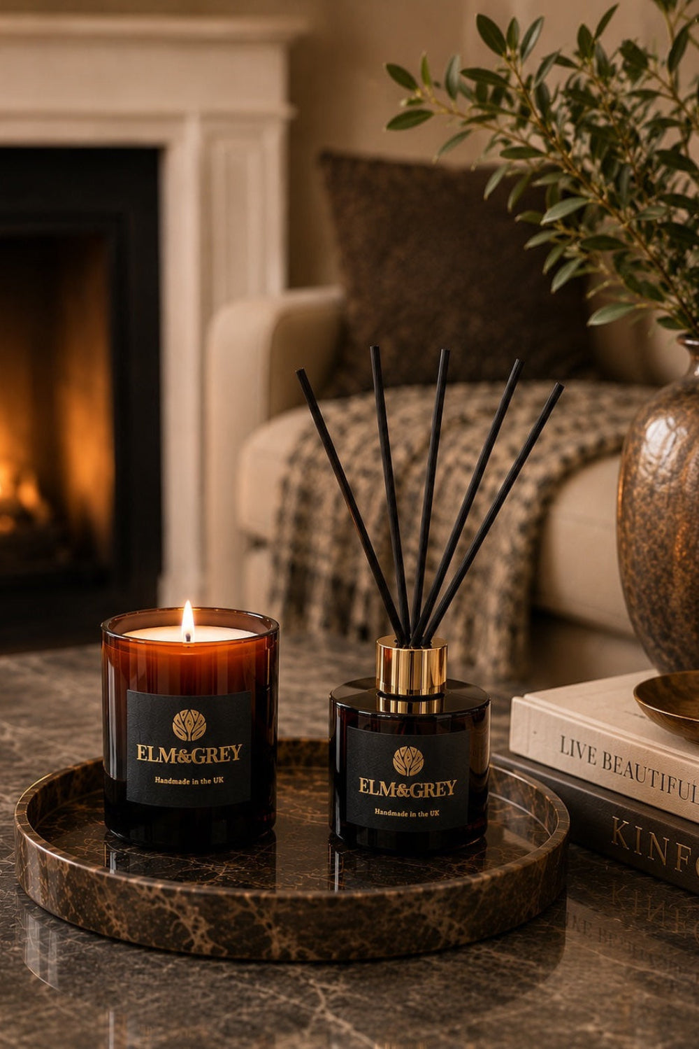 Elm & Grey Scent Ritual Gift Box contents - luxury scented candle and reed diffuser styled on a dark marble tray with lit fireplace in background