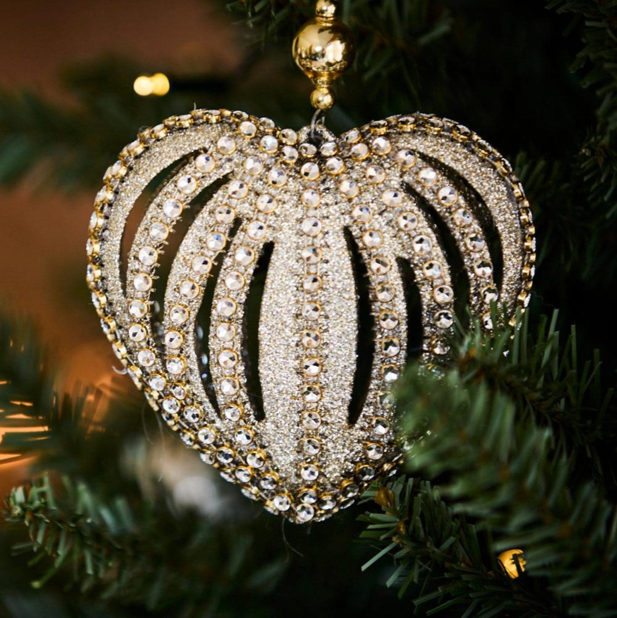 Decorative heart-shaped ornament with crystals on a Christmas tree.