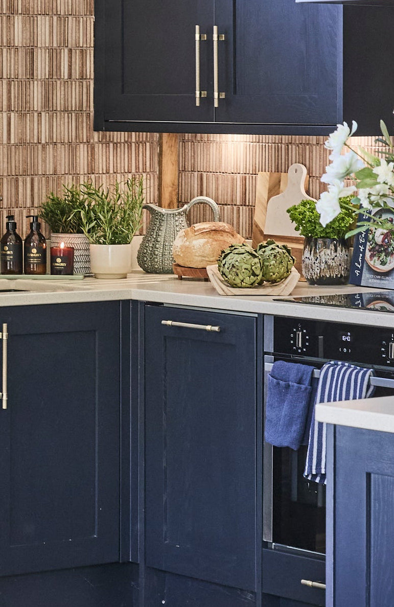 Modern kitchen with blue cabinets, stone flooring, and a dining area.