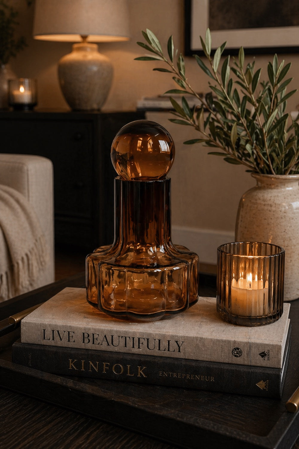 Hazel amber glass scalloped bottle with sphere stopper on stacked books with lit amber tealight Elm & Grey