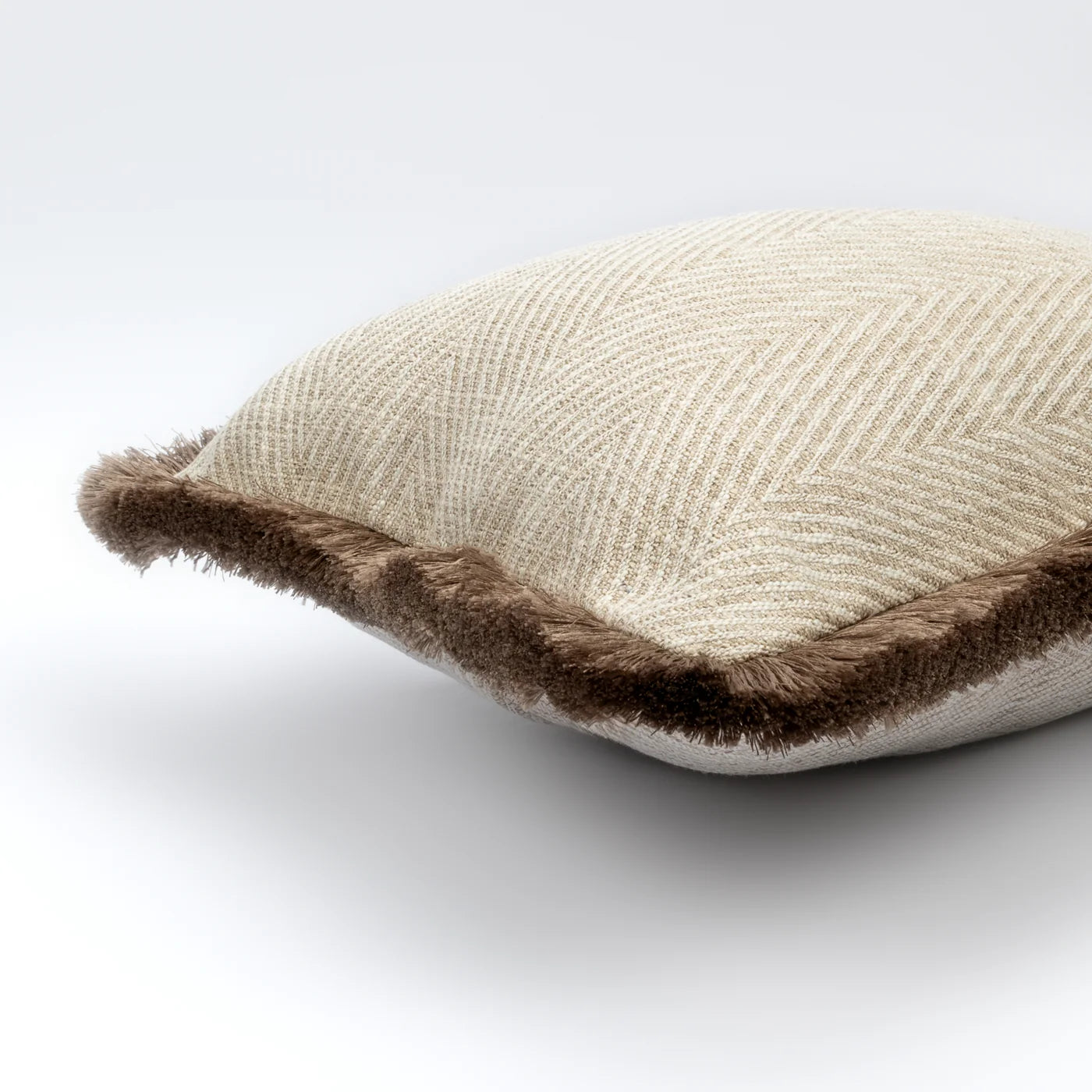 Beige pillow with brown trim on a white background