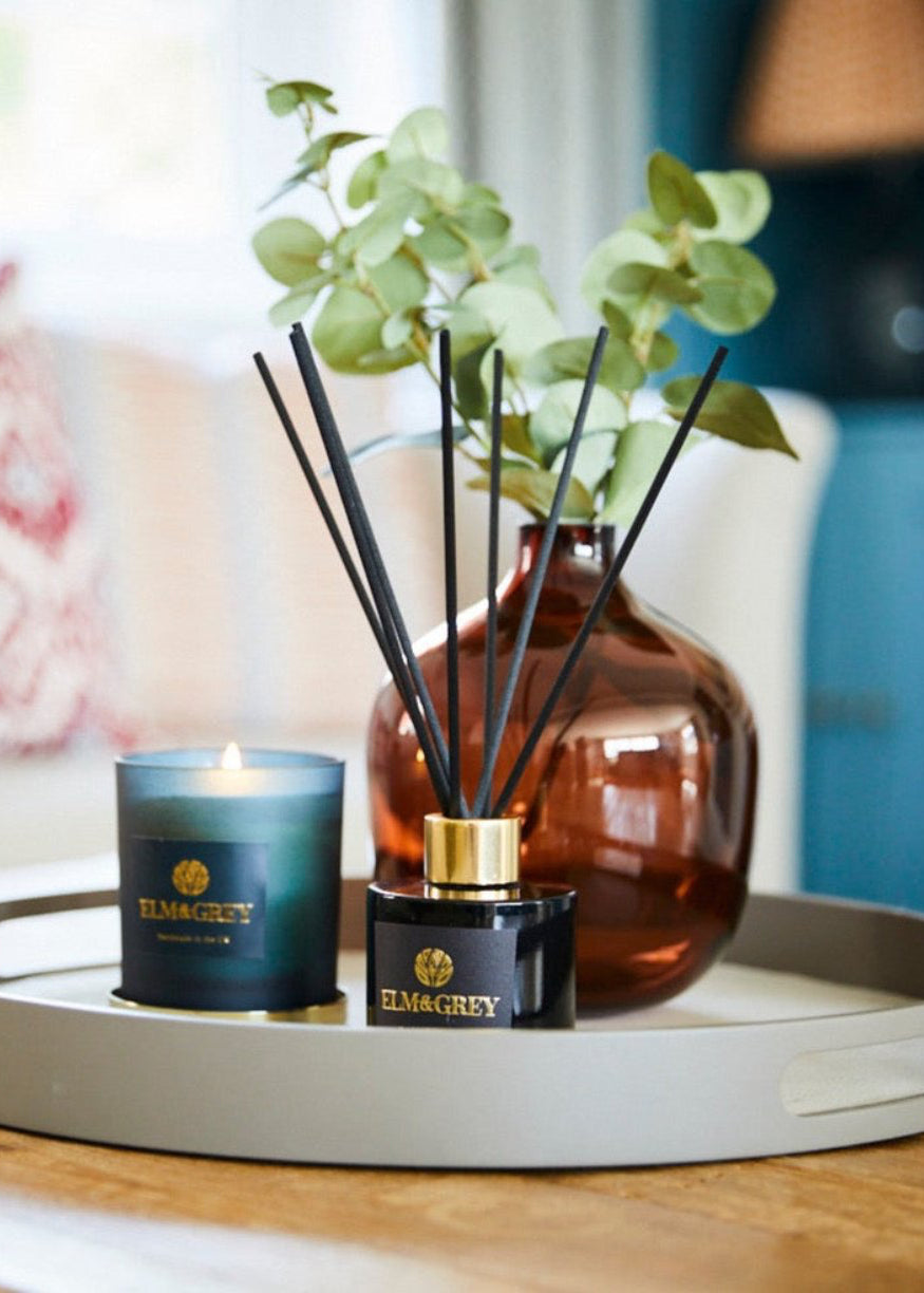 reed diffuser, candle and vase on a round tray