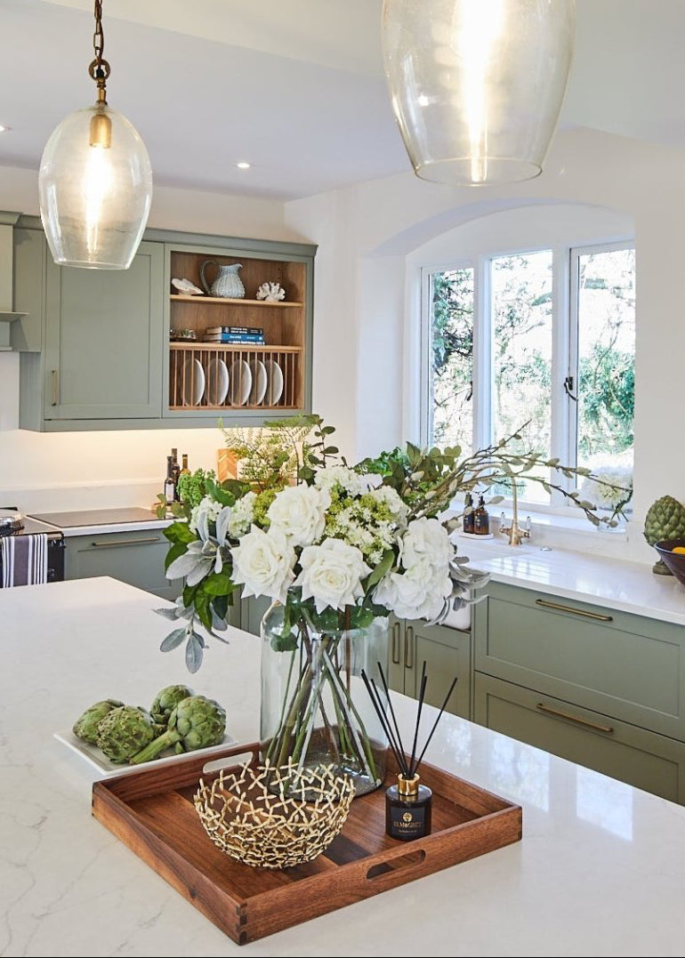 Elm & Grey Lime Basil & Mandarin Reed Diffuser on a tray with a floral arrangement decorative bowl on a white marble countertop in a kitchen
