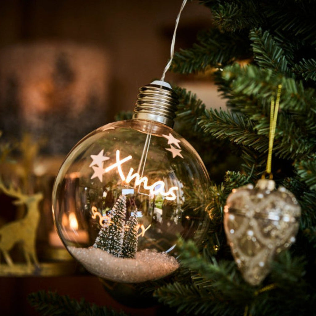 Decorative Christmas ornament with Lit 'Xmas' text on a tree