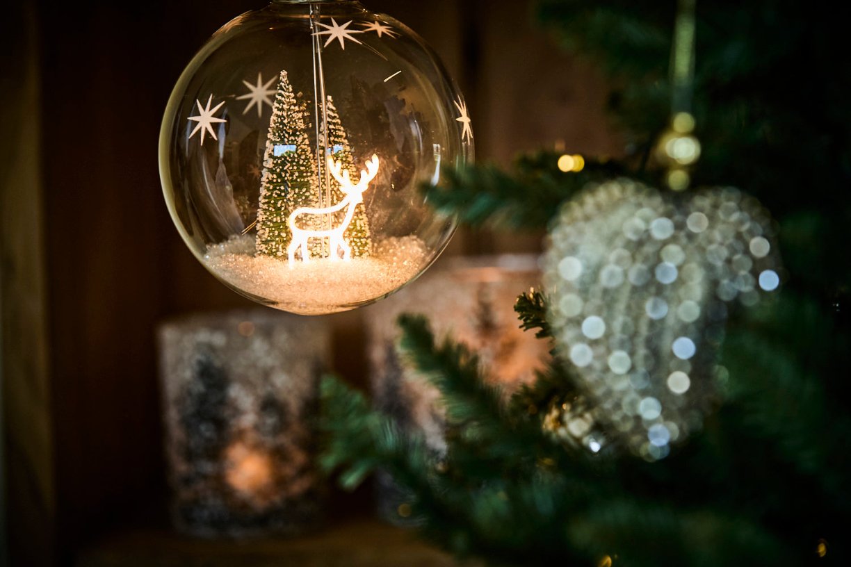 lit reindeer bauble and glitter heart on a tree