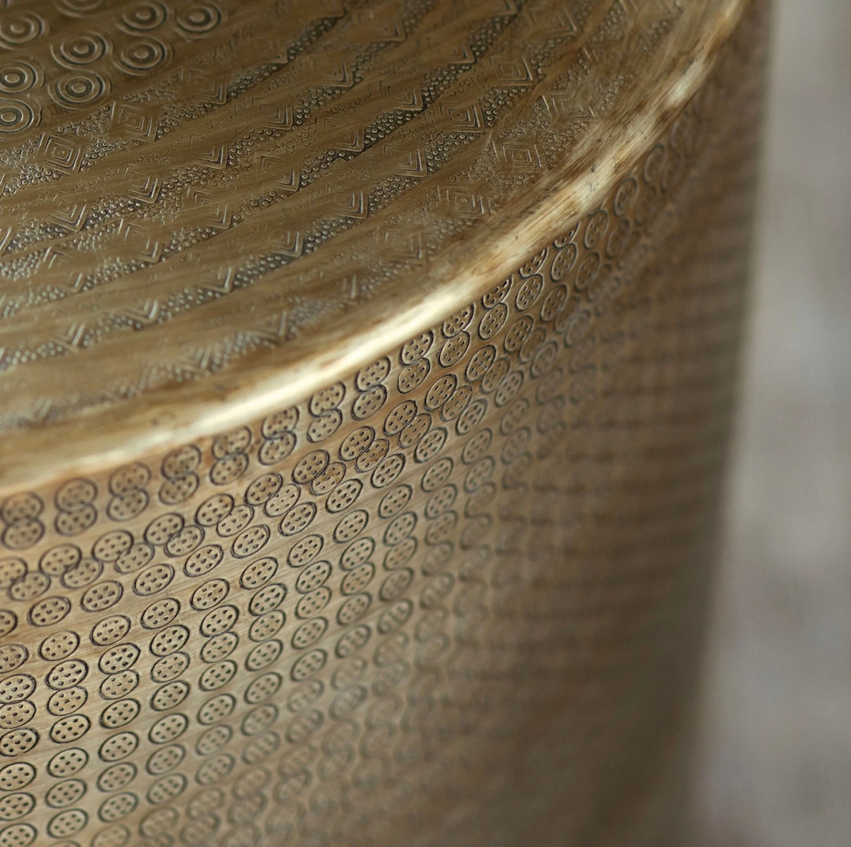 Close up of round antique brass embossed coffee table on a white background