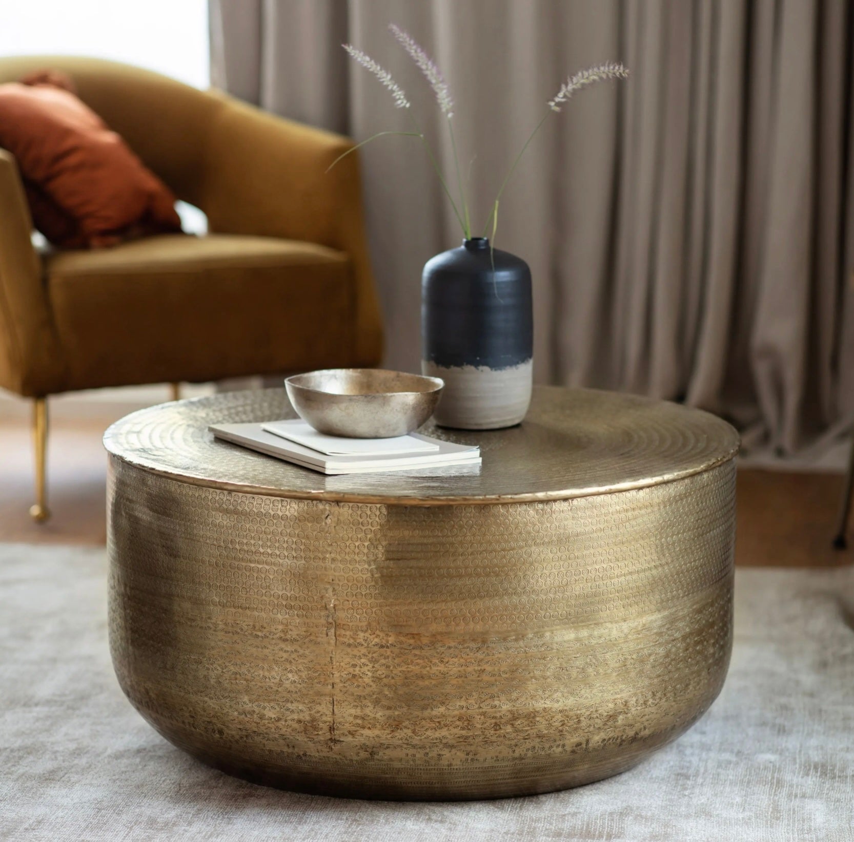Antique brass embossed coffee table with decorative items in a living room setting