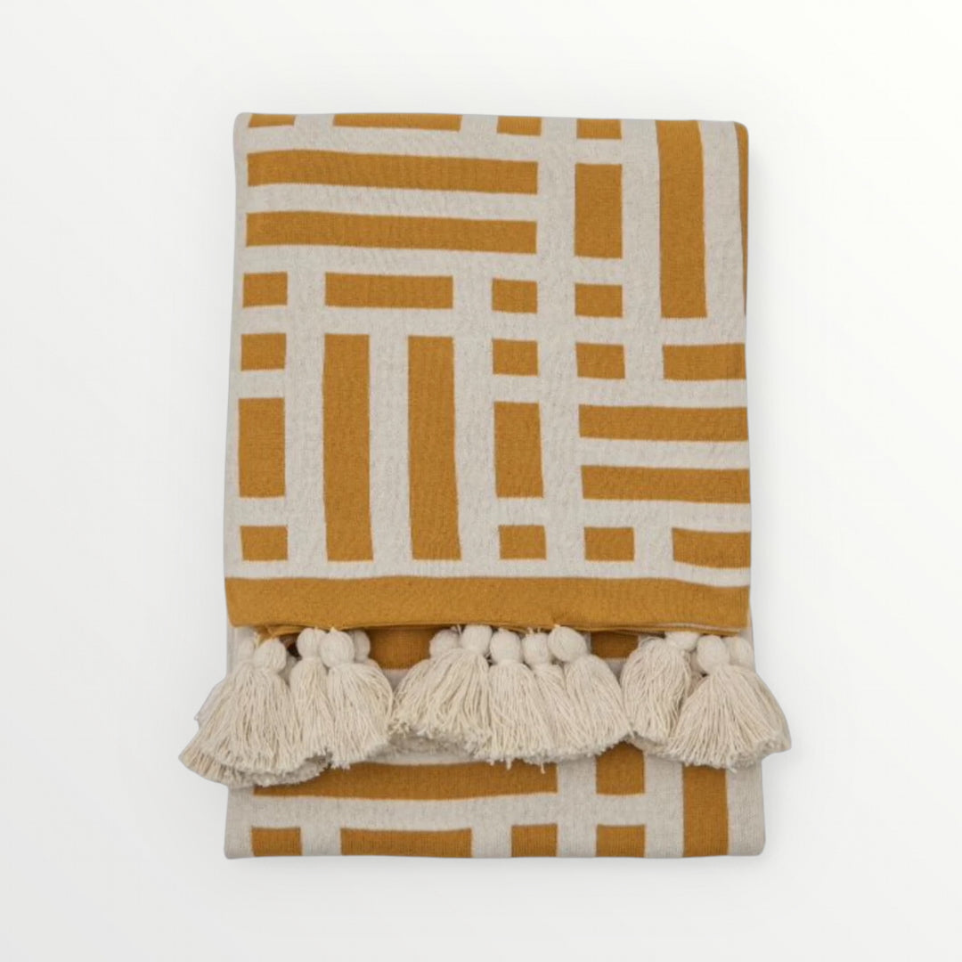 Yellow and white patterned blanket with tassels on a white background, Elm & Grey.
