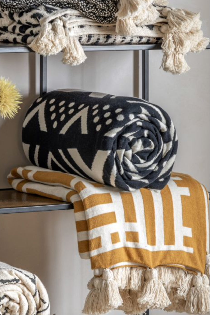 luxury weave tassel throw  on a shelf with other decorative items. Elm & Grey,