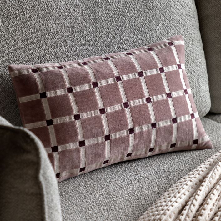 Plaid pillow on a gray sofa with a textured wall background