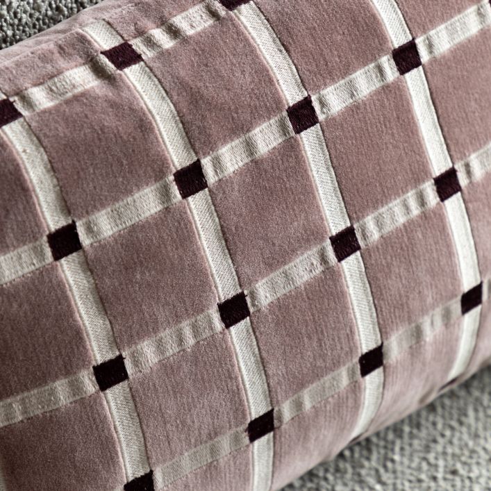 Close-up of a pillow with a plaid pattern in shades of pink, gray, and black.
