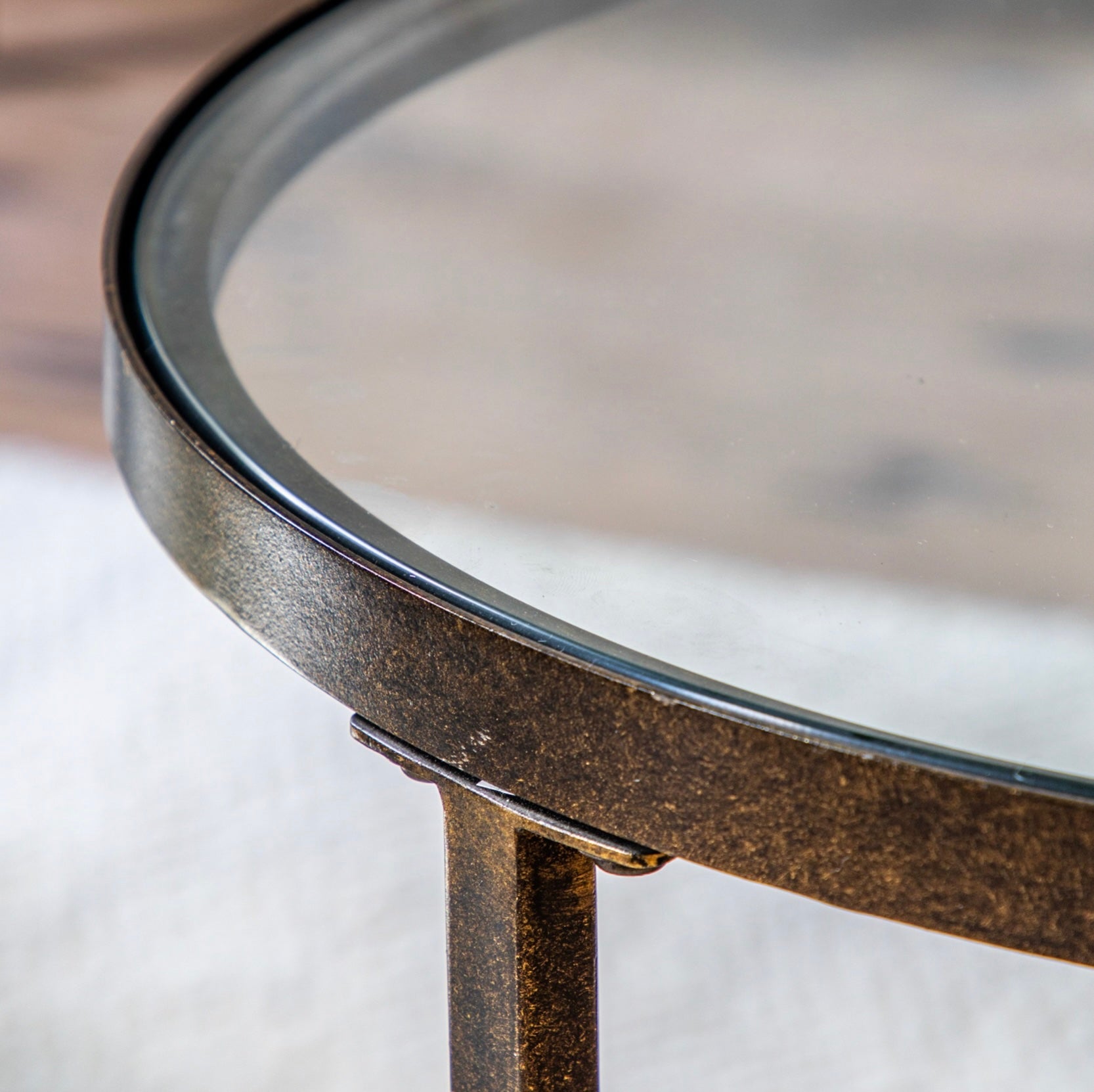Close up of glass coffee table with bronze metal base on a blurred background