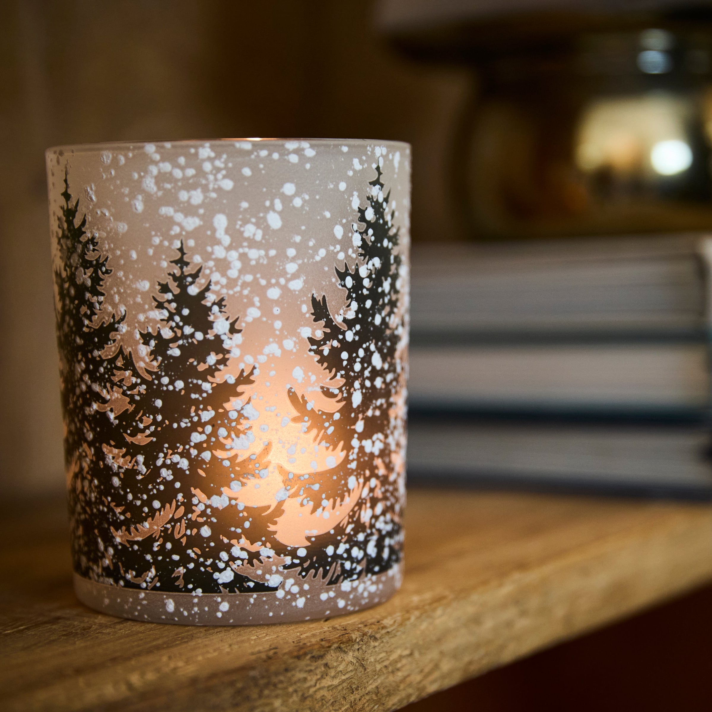 Decorative candle with a winter scene design on a wooden surface