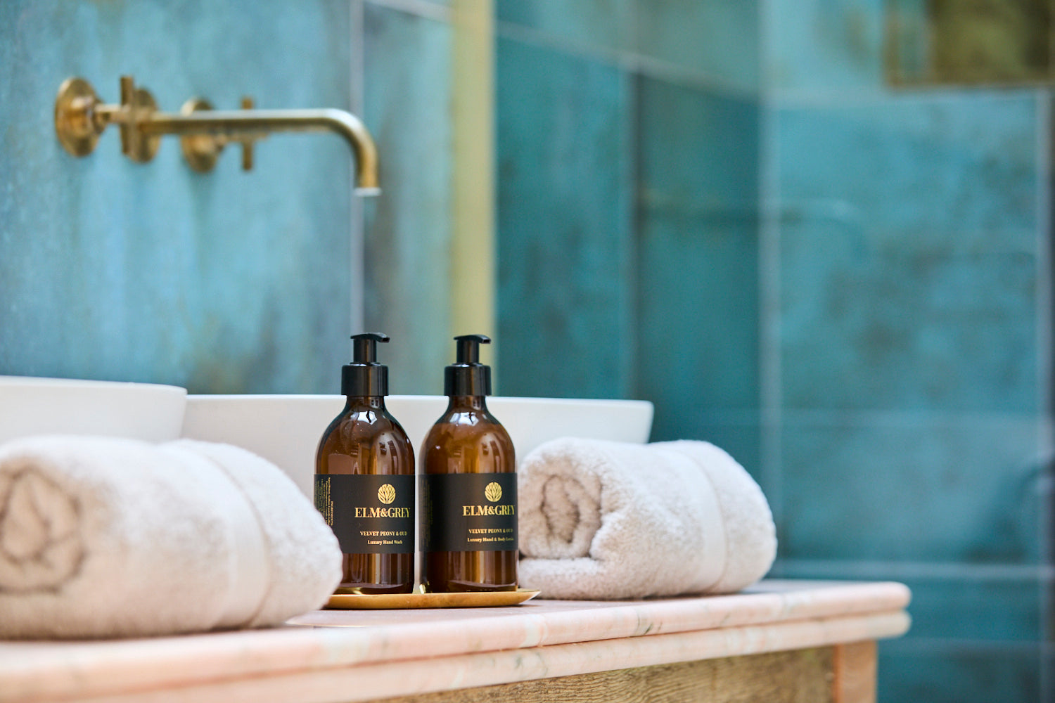 Two brown bottles with black labels on a marble surface in a bathroom setting.