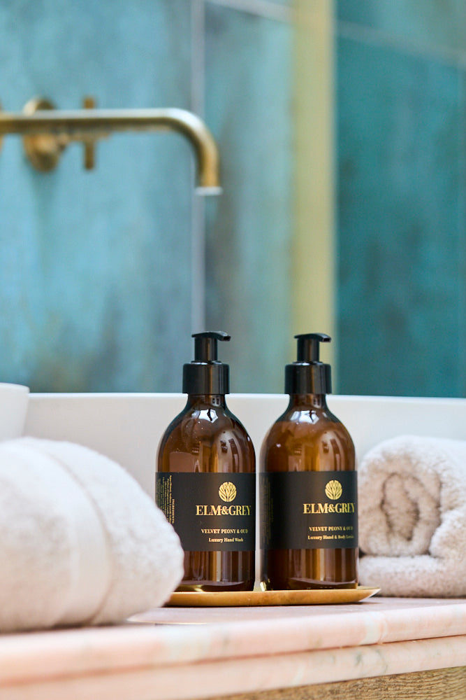 Two brown bottles with black labels on a marble surface in a bathroom setting.