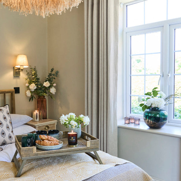 Lifestlye Image of a bedroom with a breakfast tray and vase with faux flowers in it on a window sill