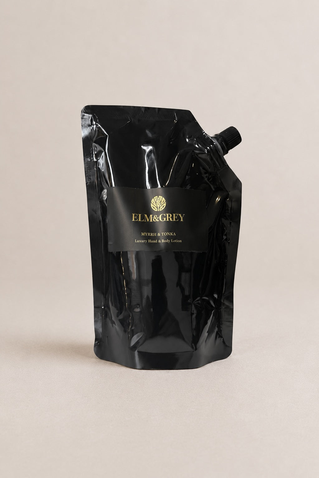 A black resealable stand-up pouch with a black label reading ELM&GREY, photographed on a plain warm beige background.