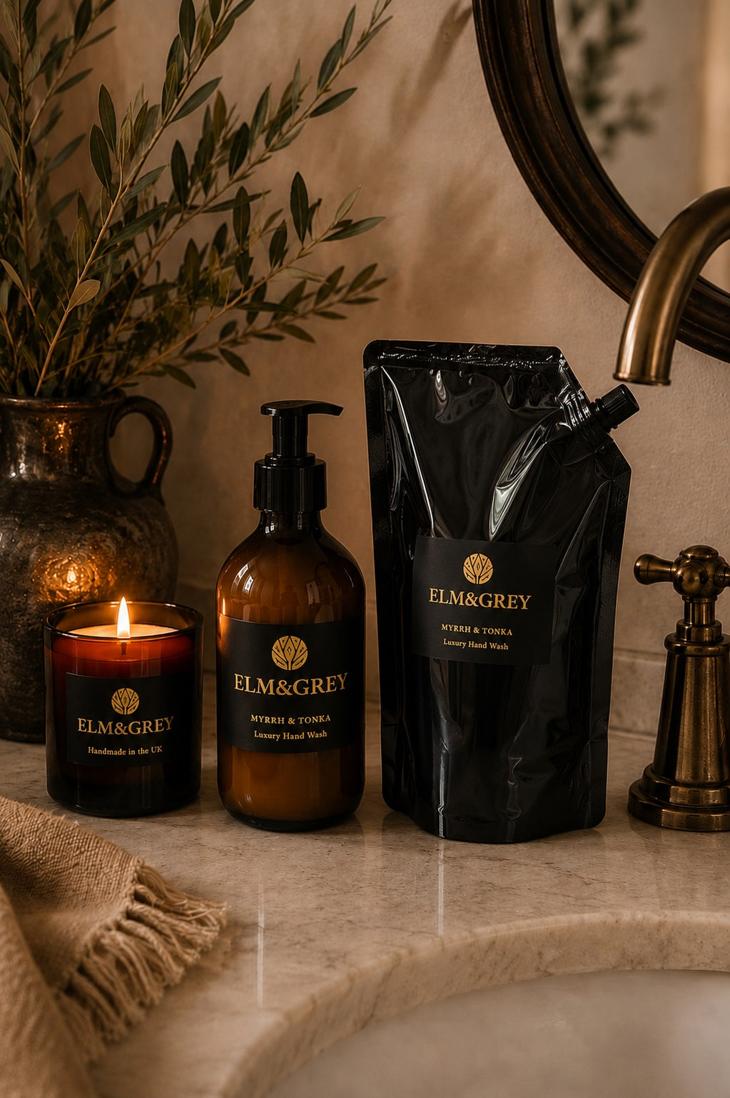 Bathroom counter with Elm & Grey Myrrh and Tonka candle, hand and body wash, Hand wash refill  pouch and bath towel.