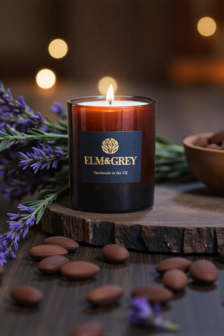Elm & Grey candle on a wooden block with lavender and almonds around it.