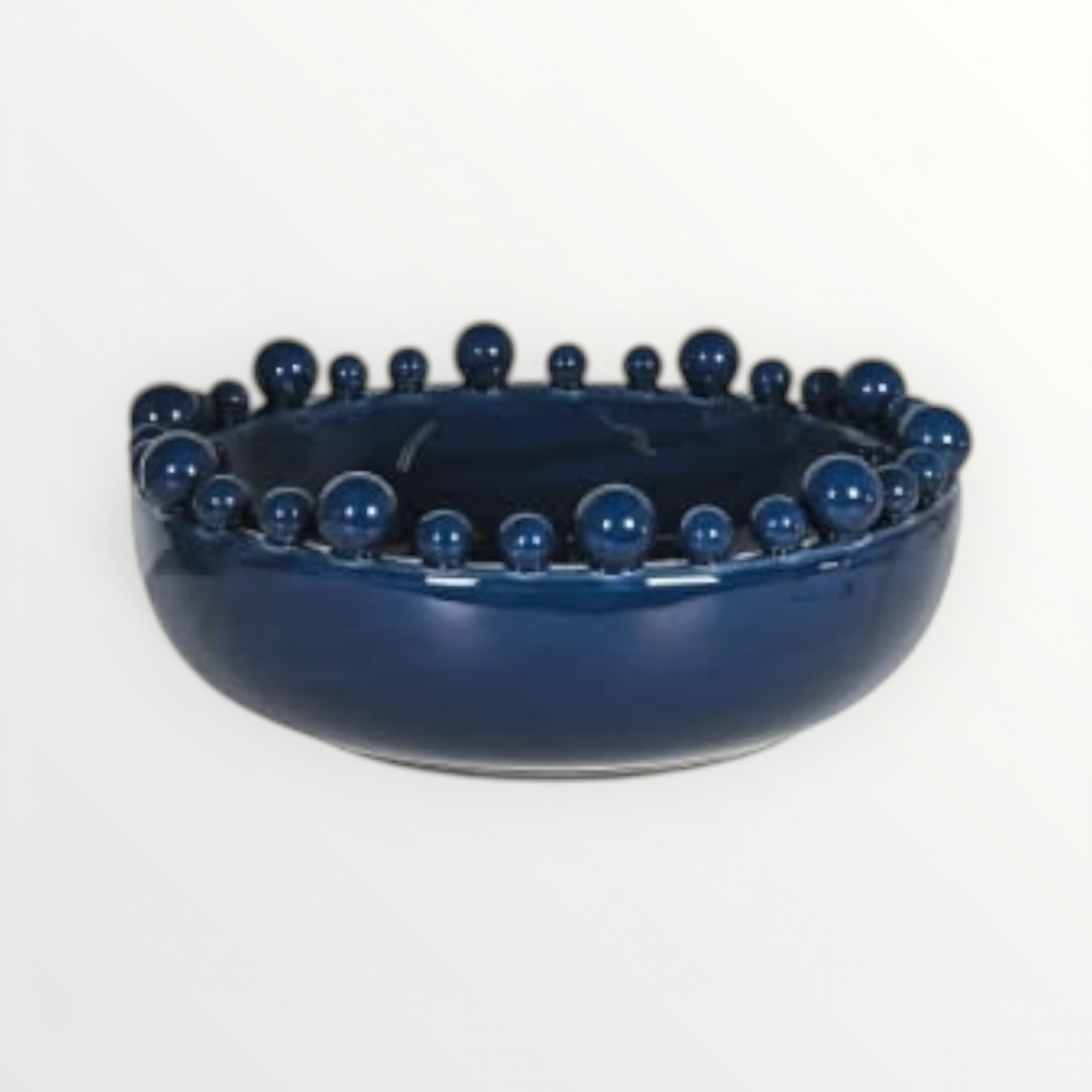 A navy blue ceramic bowl with a bobble edged design on a white background.