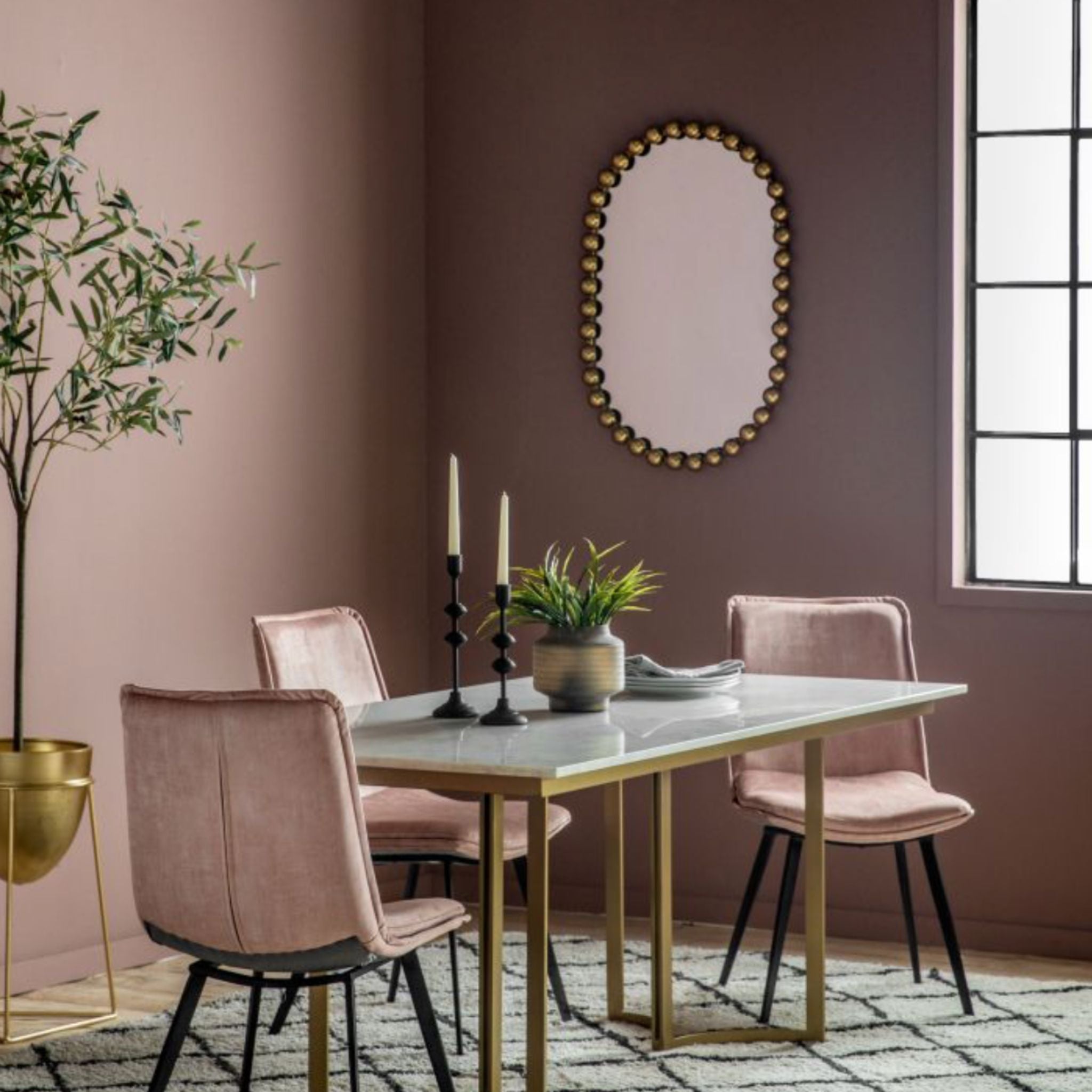 Dining room with pink walls, marble table, and pink chairs.