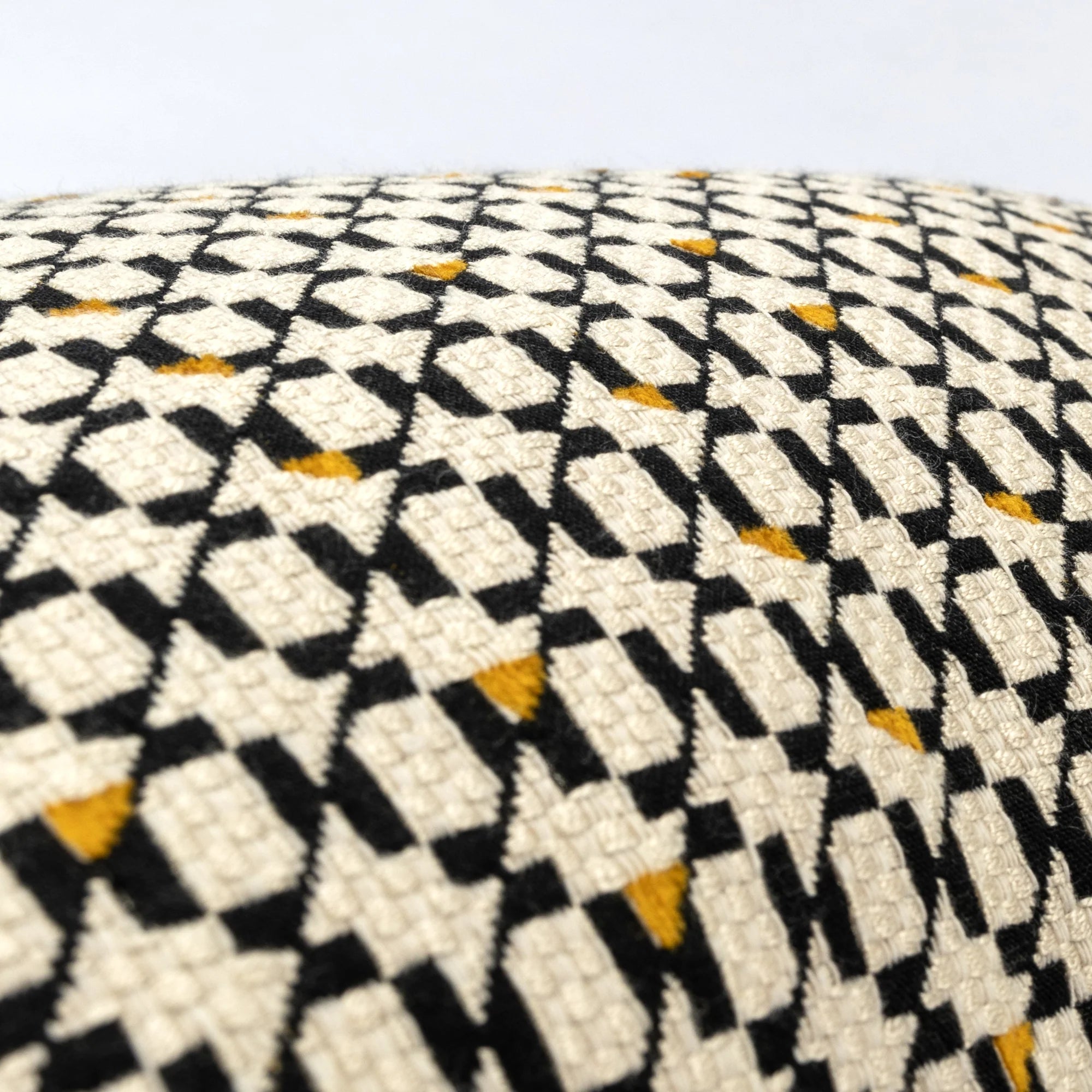 Close-up of a geometric patterned cushion with black, white, and yellow colors.