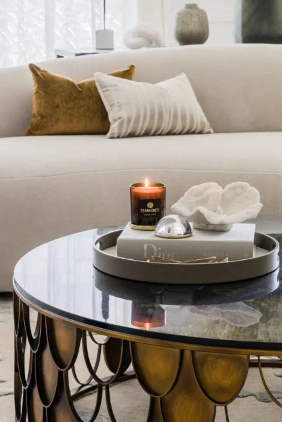 Living room with a coffee table featuring a candle and decorative items, with a couch in the background.