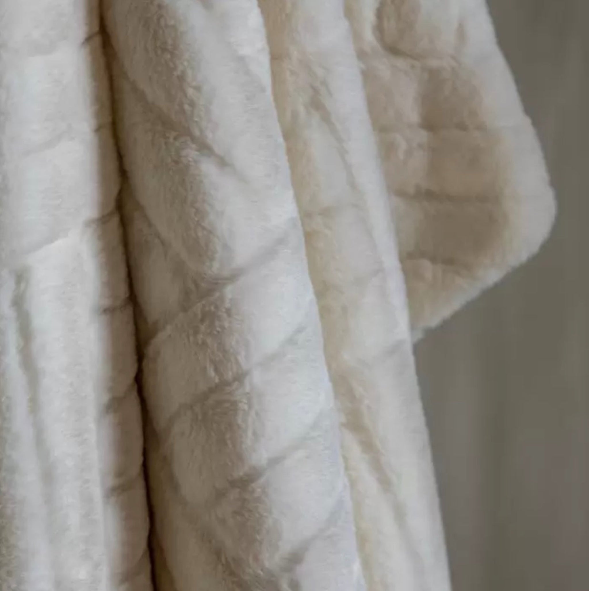 Close-up of textured beige cream throw with a neutral background