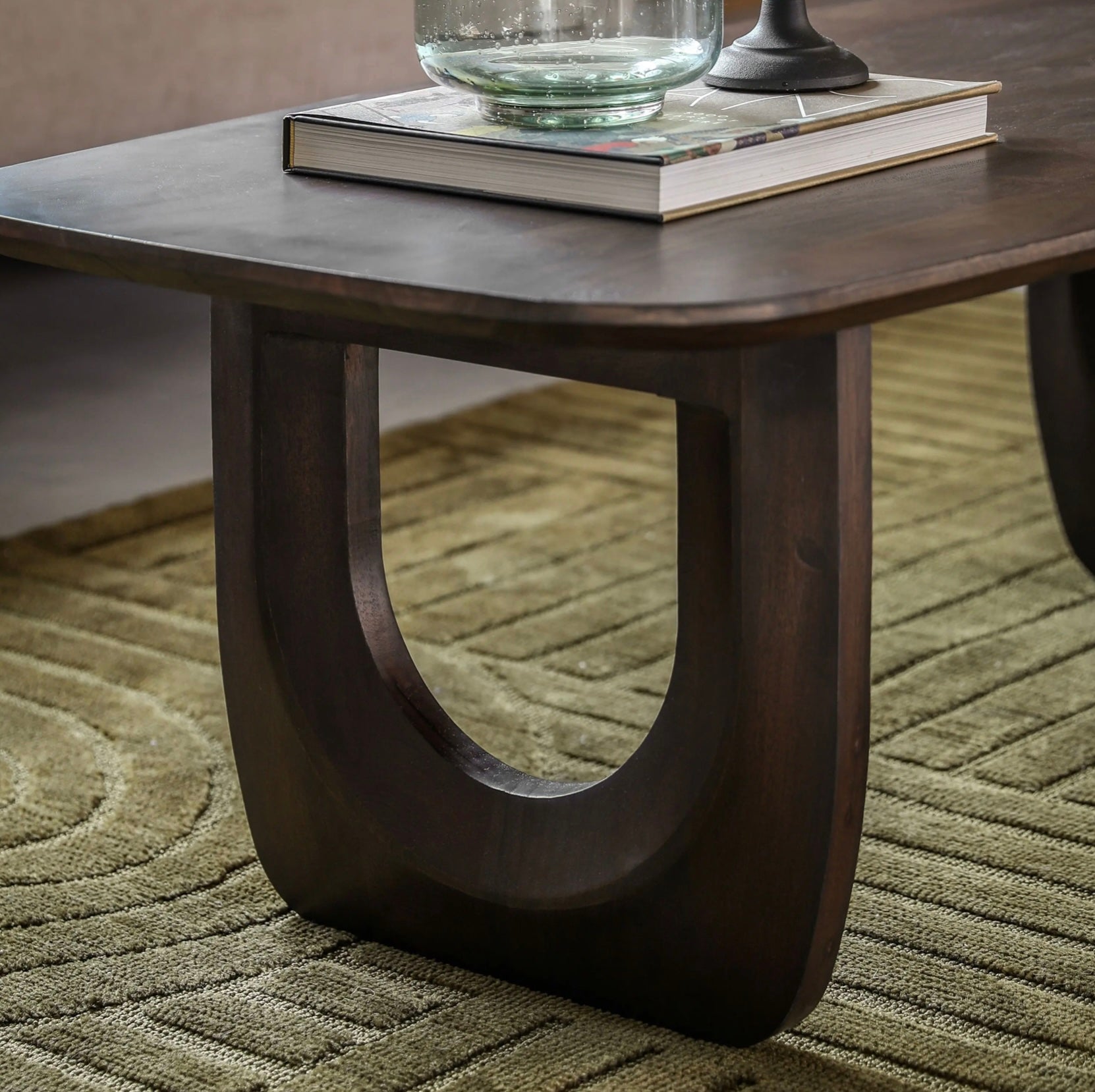 Walnut mango coffee table with a book and glass container on a carpeted floor