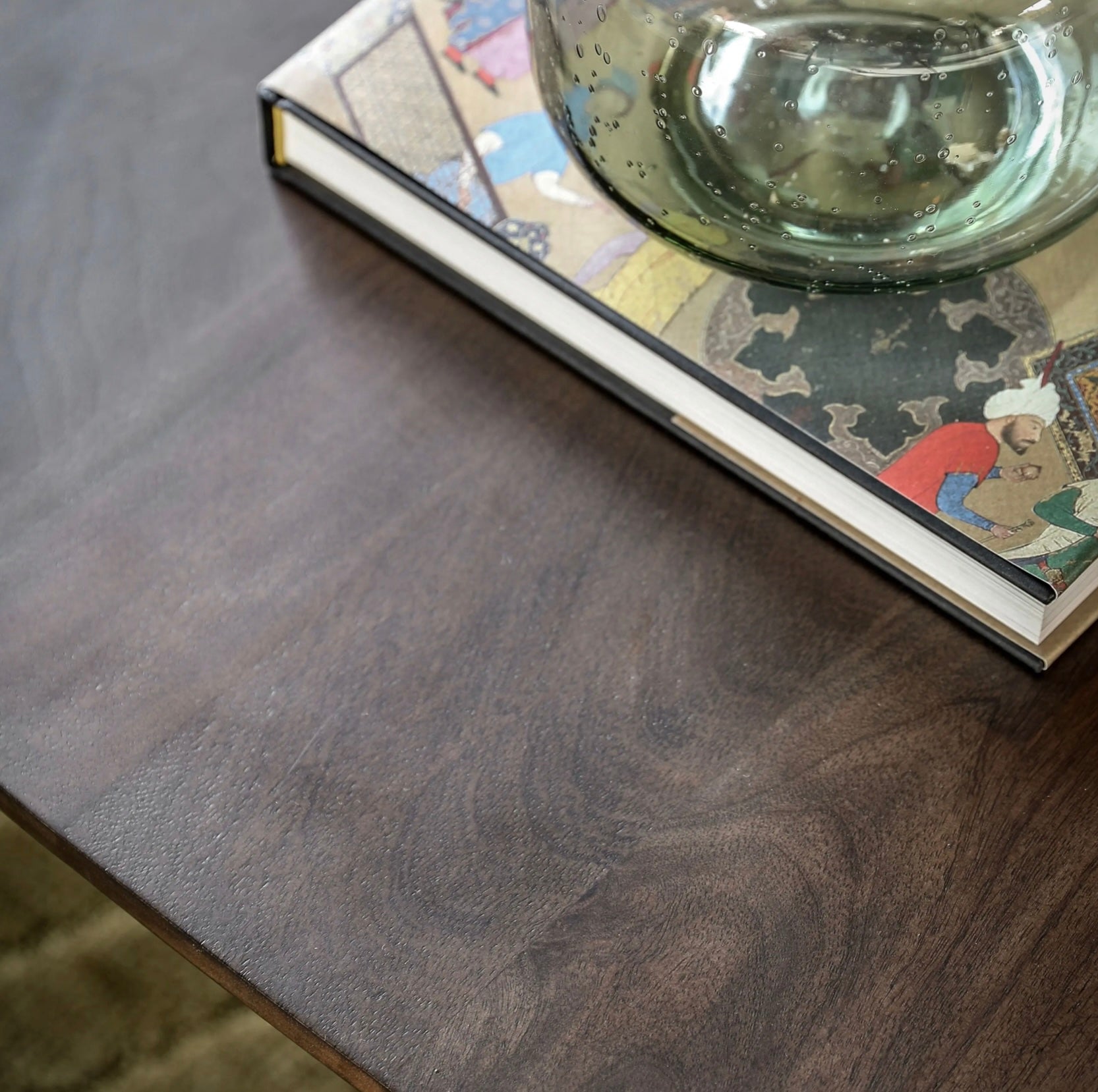 Glass container on a book with a wooden mango wood coffee table surface