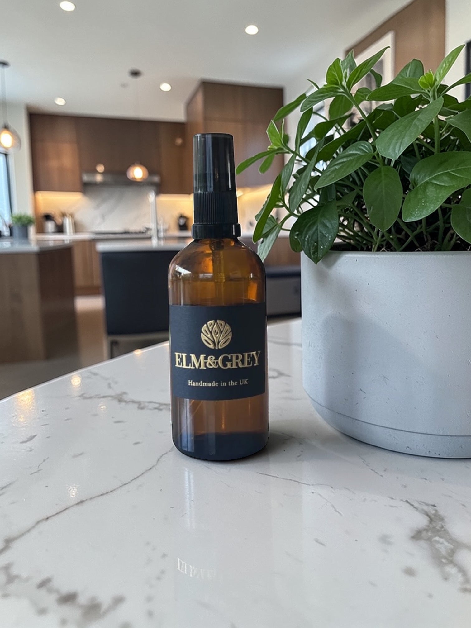 Elm & Grey  Room Spray Bottle on a kitchen counter with a plant in the background