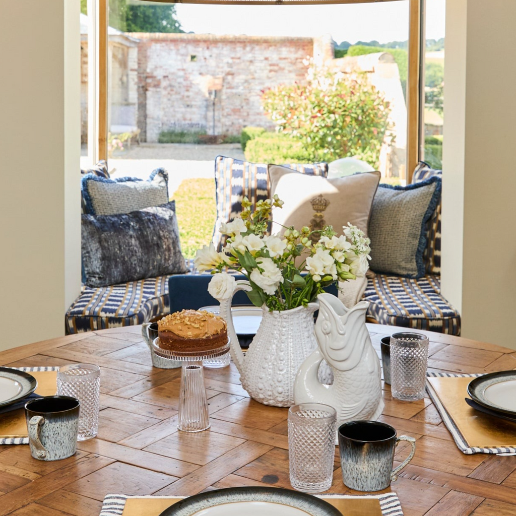 Jacquard Blues Fringed 45 x45 cushion on a window seat with gluggle jug on a kitchen table