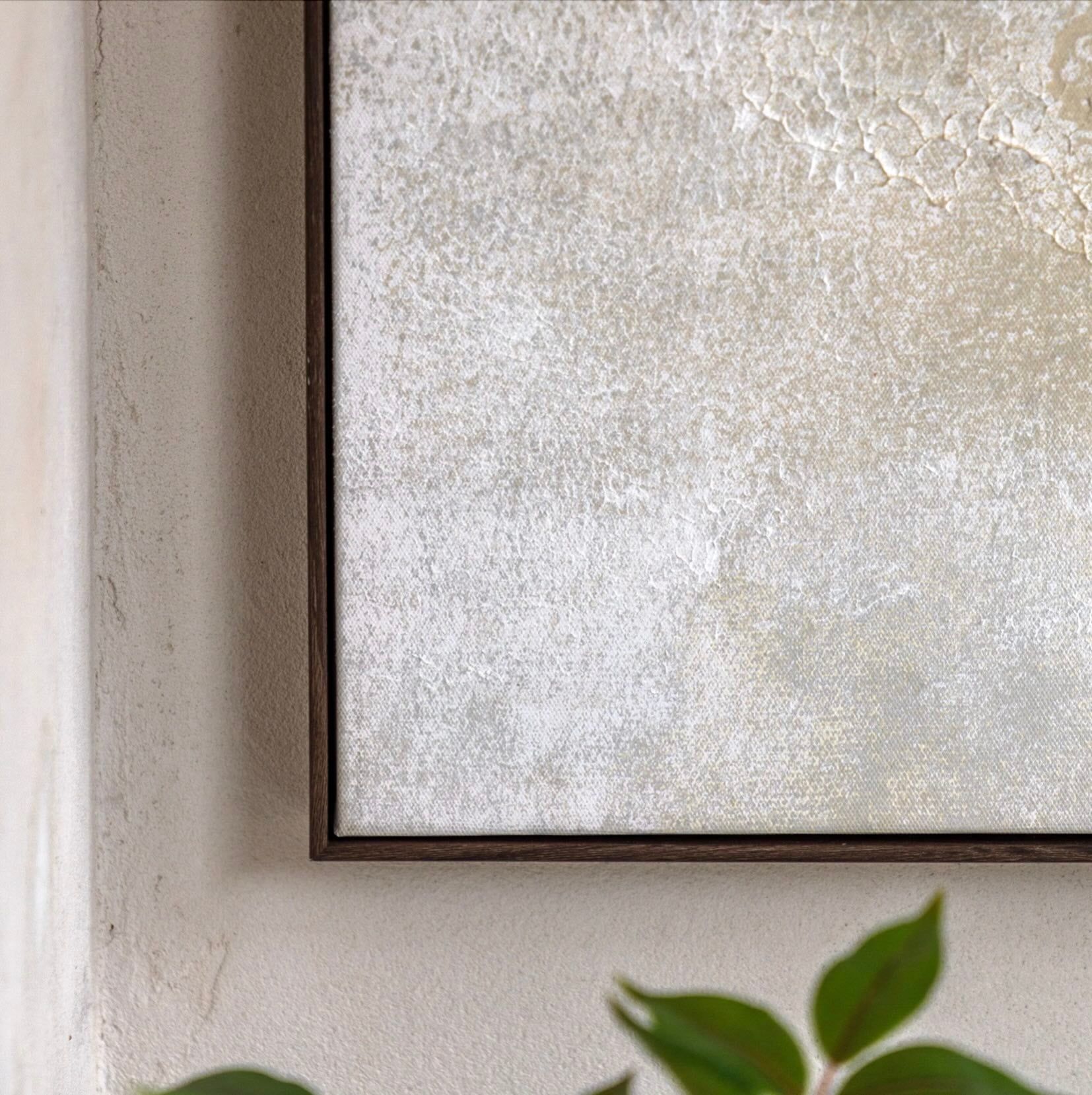 Textured wall with a framed piece of art and green leaves at the bottom by Elm & Grey