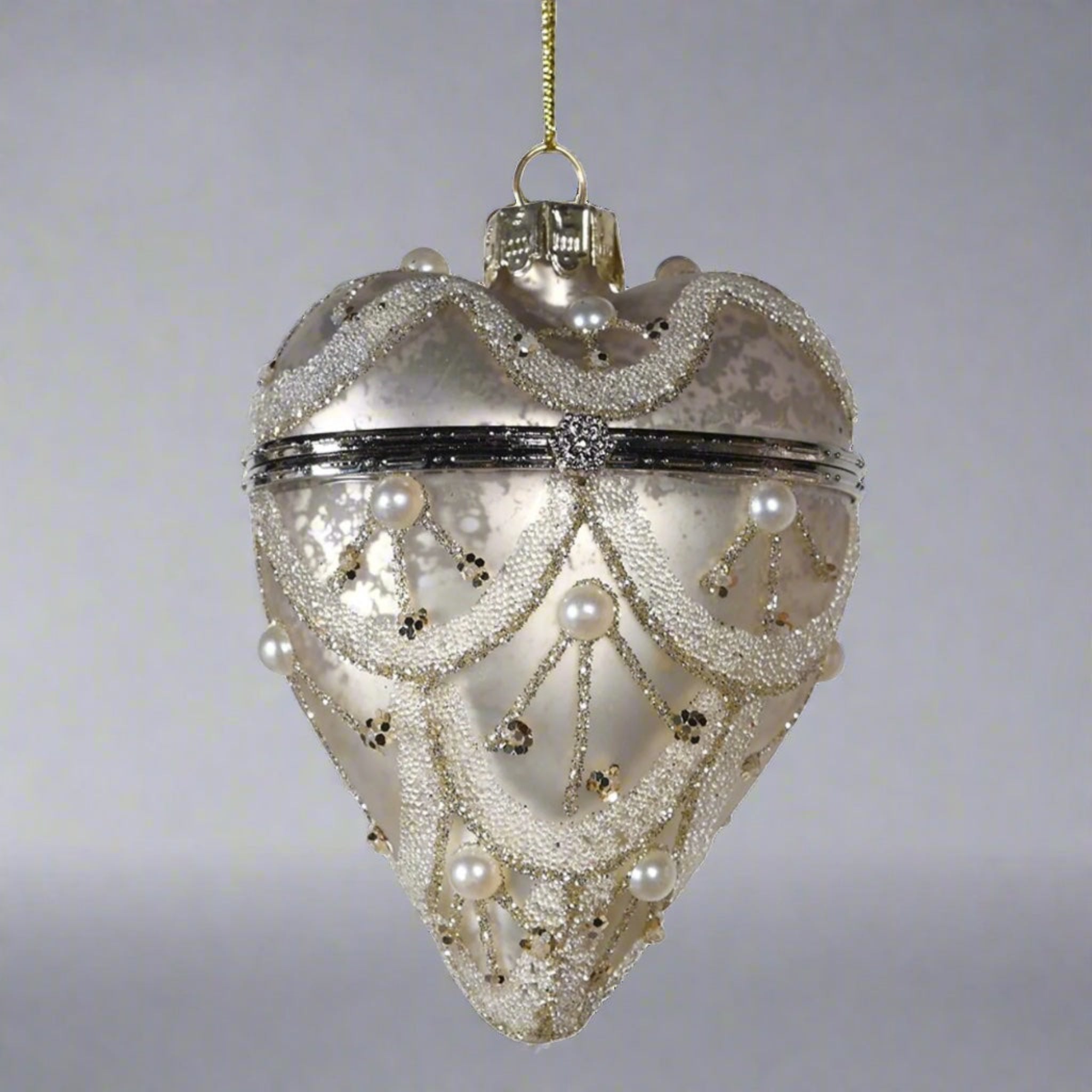 Decorative heart-shaped ornament with pearl-like beads on a gray background