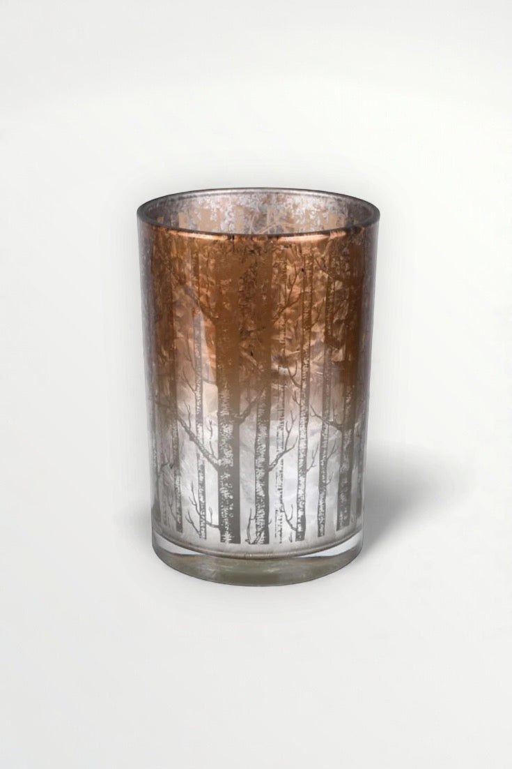 Decorative glass candle holder with tree pattern on a white background