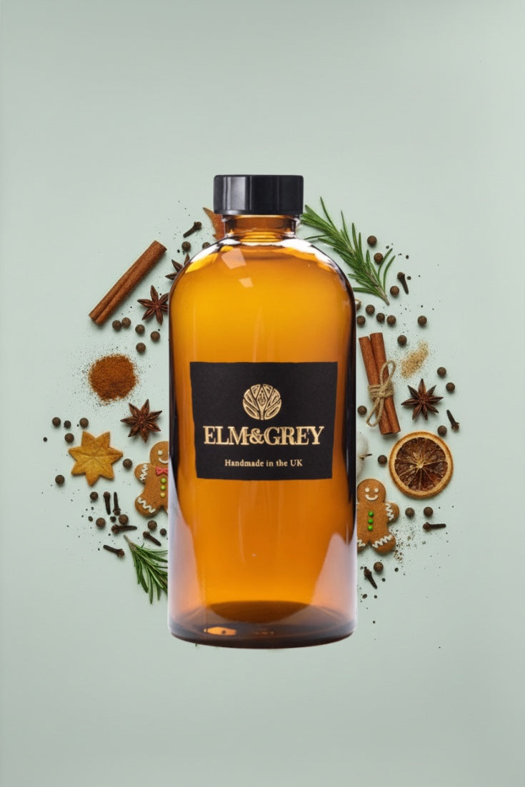 Bottle of Elm & Grey diffuser refill liquid on a light green background with spices and herbs.