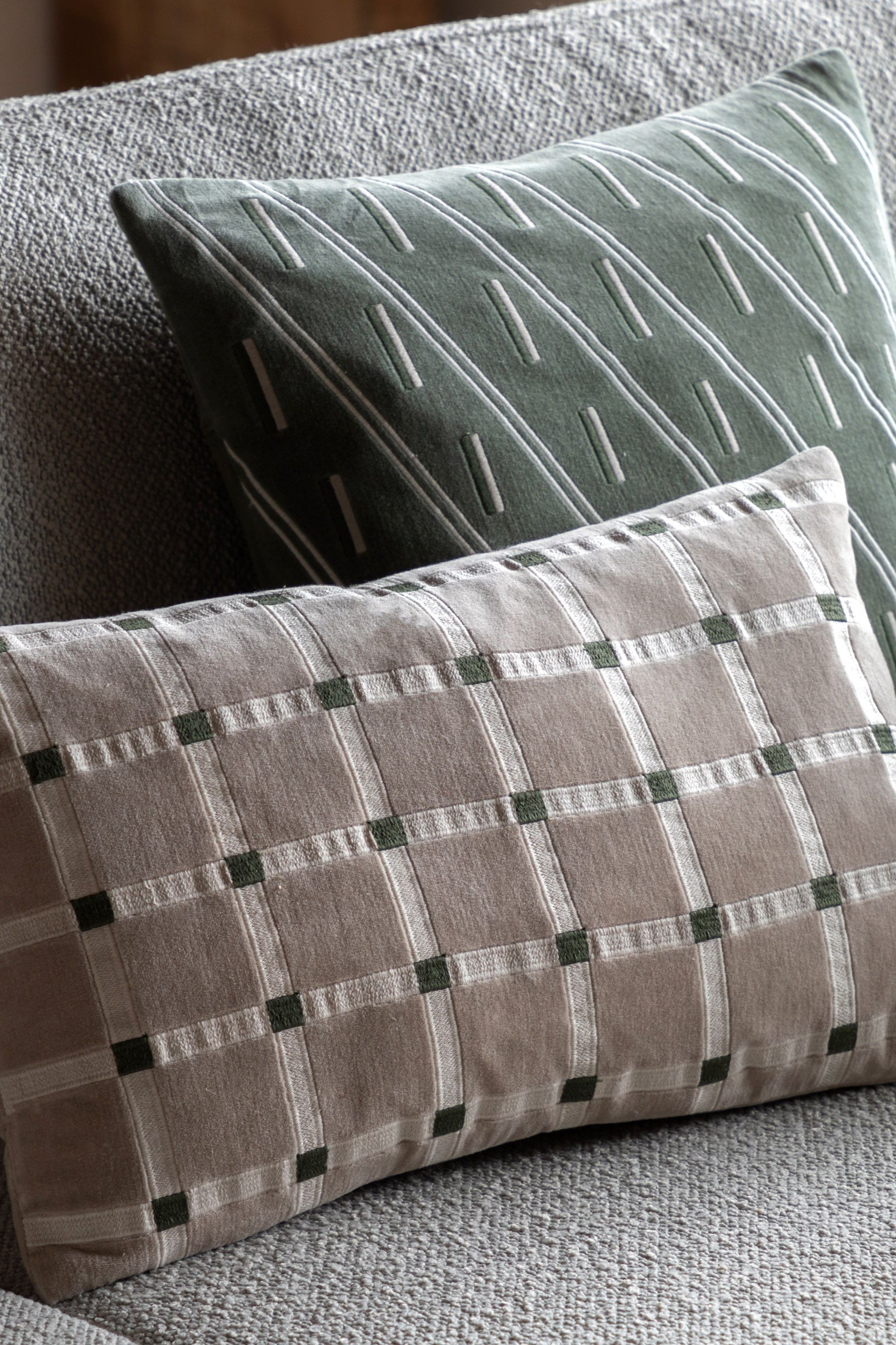 Two patterned pillows on a textured sofa