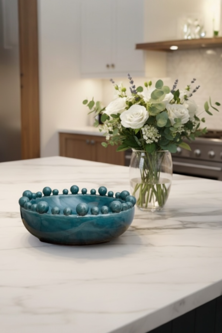 Teal bowl and vase with flowers on a kitchen counter