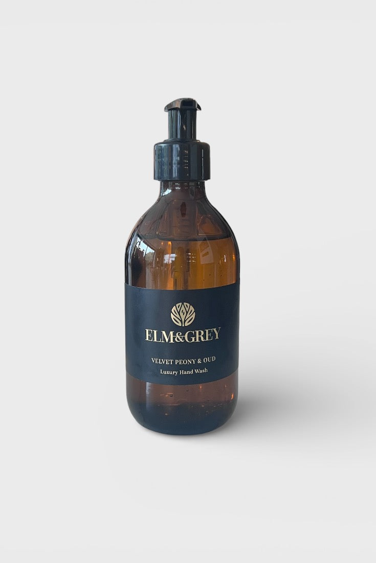 Amber glass bottle with black pump and 'Elm & Grey' label on a white background