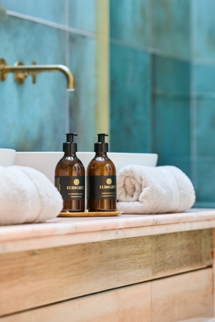 Two brown bottles with black labels on a wooden surface in a bathroom setting.