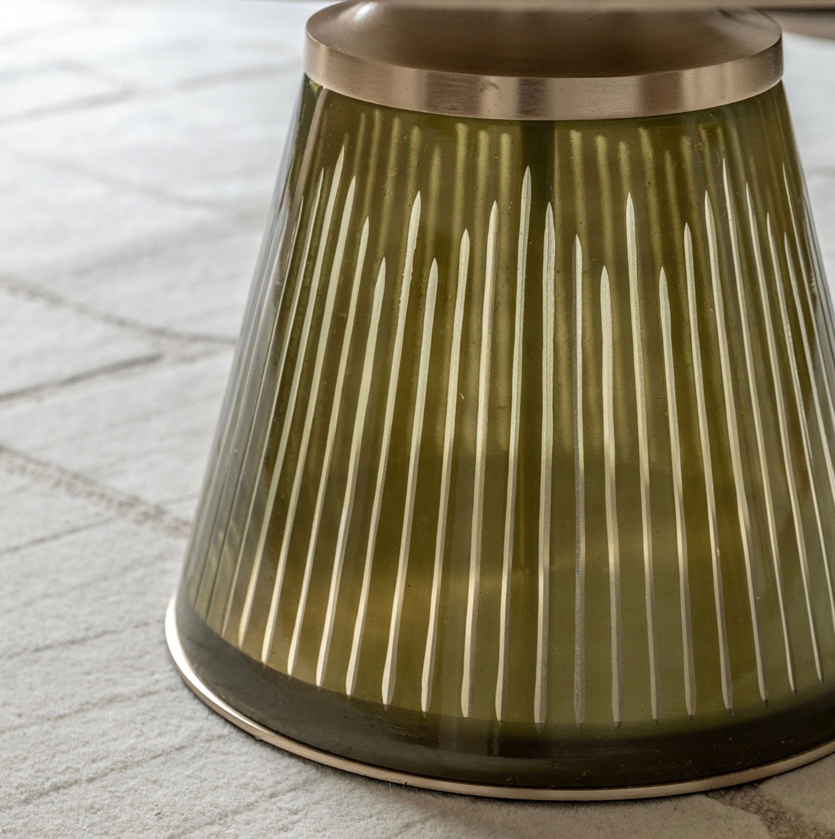 Decorative glass coffee table base with ribbed design on a textured surface