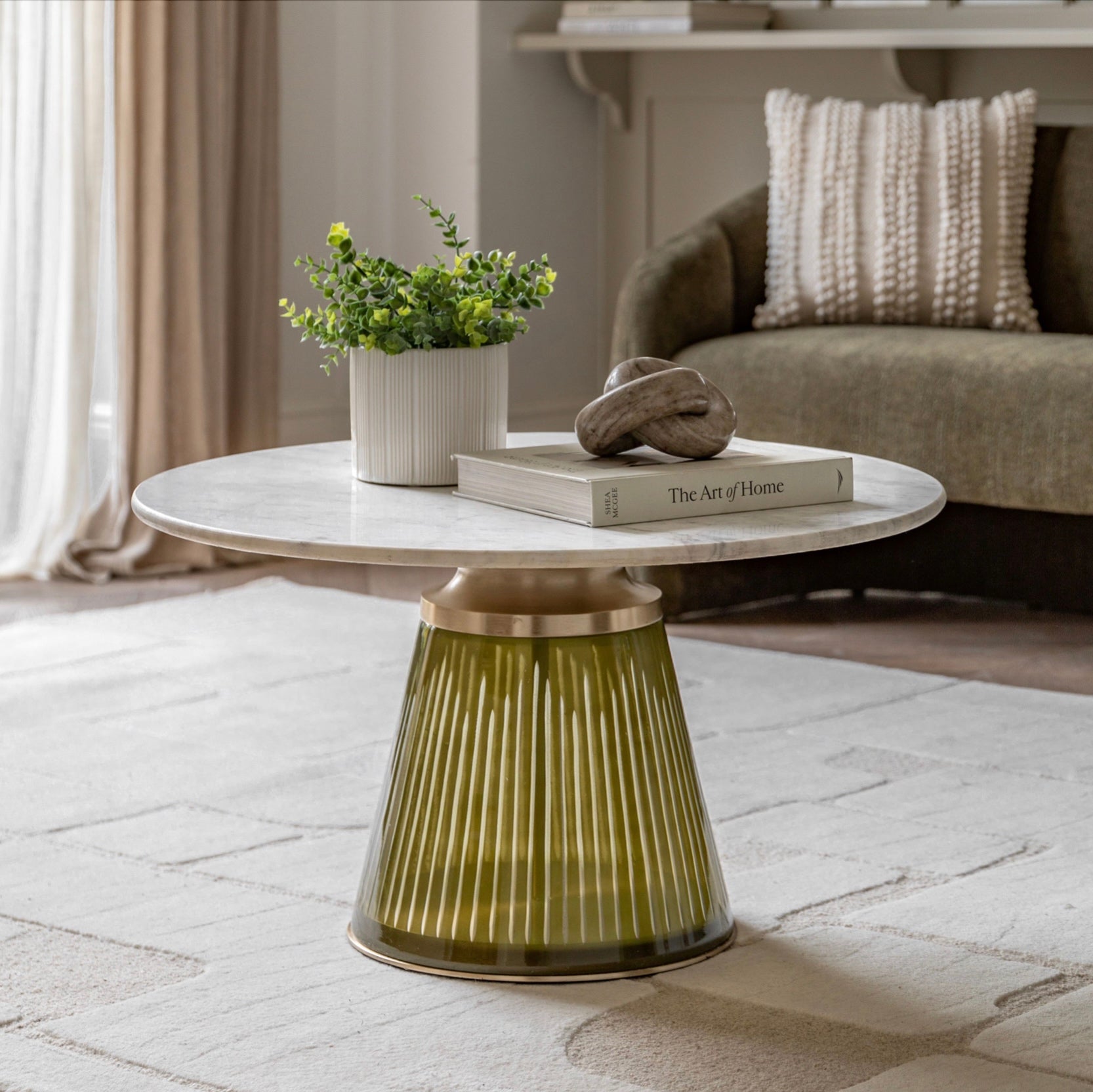 Round marble coffee table with decorative items in a living room setting