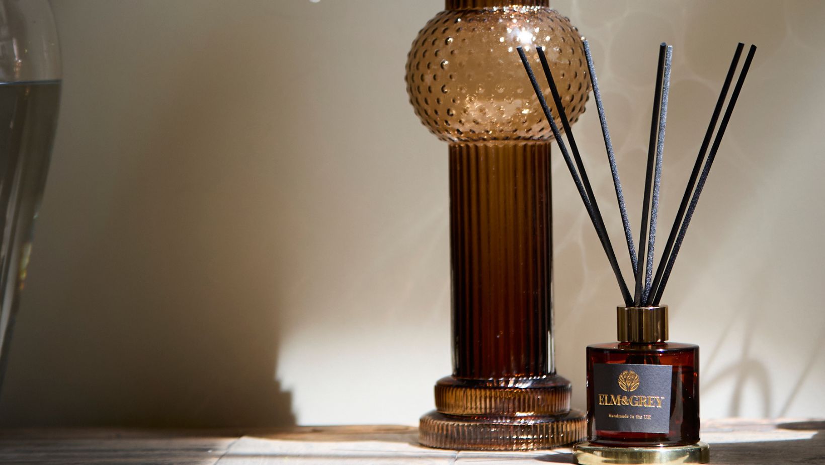 image of a amber coloured diffuser on tha table next to a candle holder