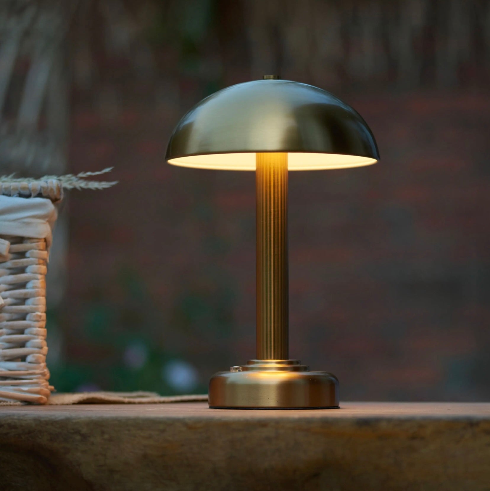 Warm brass table lamp on a wooden surface with a blurred natural background