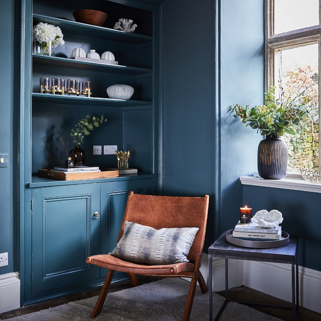 Cosy room with a brown leather chair, blue walls, and decorative elements, Elm & Grey.