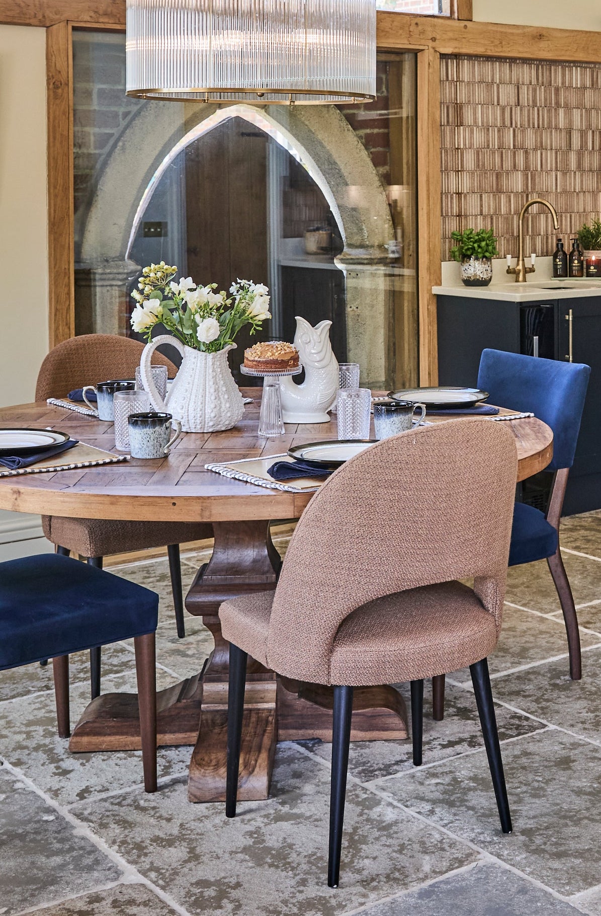 Modern kitchen with blue cabinets, stone flooring, and a dining area.