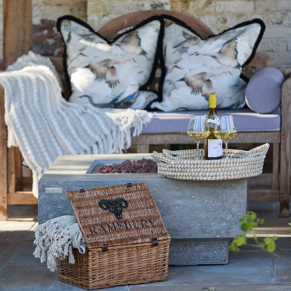 Outdoor dining and relaxing with cushions and woven seagrass trays with wine on and Ramsbury Brewery basket containing blankets
